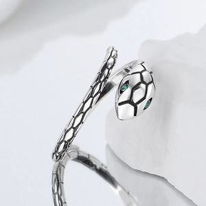 925 silver snake ring with green stone eyes and scale texture on stone background