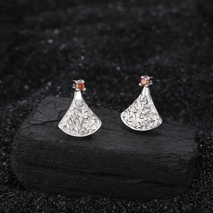 Silver fan-shaped drop earrings with floral embossing and red zircon on a black stone