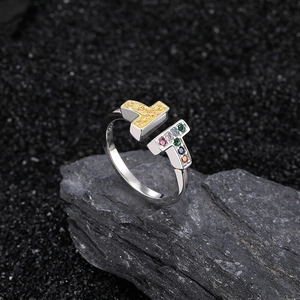 Silver and gold double T open ring featuring colored gemstones on a textured rock base