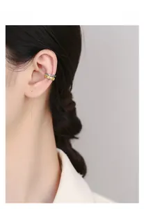 Detailed view of silver and gold cuff earrings with colorful cubic zirconia stones