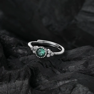 S925 sterling silver ring with green center stone and side gems on charcoal background