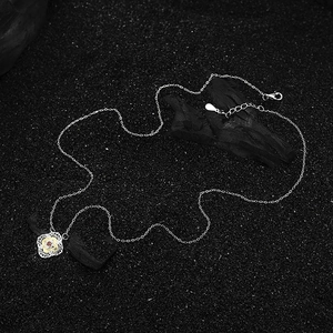 S925 sterling silver clover necklace with red garnet pendant on black sand background