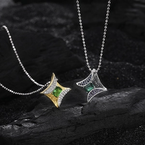 Detailed macro view of two vintage star pendants with green gemstones on dark stone