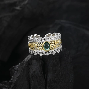 Détail macro d'une bague nid d'abeille bicolore avec pierre verte ovale et pavé de diamants