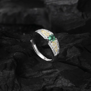 S925 silver angel wing ring with green zircon and gold accents on black charcoal