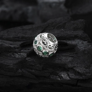 S925 sterling silver hollow charm with green zircon stones on dark stone background