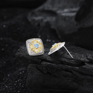 Retro square S925 silver earrings with blue zircon and gold floral accent on dark stone