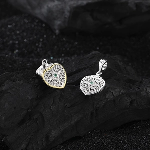 Macro detail of S925 silver heart pendants with intricate filigree and green gemstone