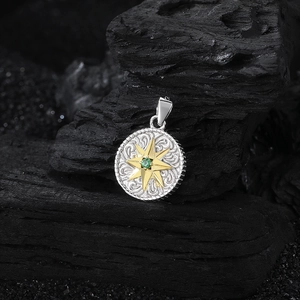 Detail of s925 silver star pendant with golden relief and green gemstone inlay