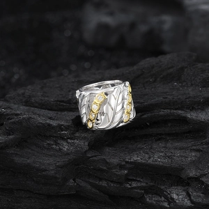 S925 sterling silver feather ring with gold edges and micro-pave crystals on dark wood