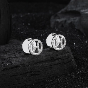 Boucles d'oreilles lettre H en argent S925 et cristaux sur fond texturé noir de luxe