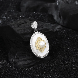 Detail of S925 silver oval pendant with mother of pearl and pearl inlay on black rock