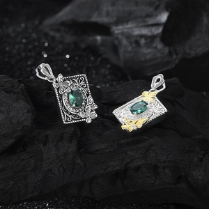 Close-up of s925 silver butterfly pendants with green zircon and vintage book pattern