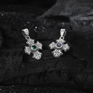 Macro shot of S925 sterling silver cross pendants with emerald green and deep blue gems