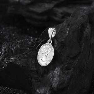 Macro detail of S925 sterling silver mermaid crown portrait pendant on dark stone