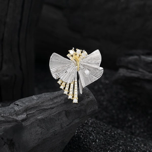 Artistic silver pleated pendant with gold diamond-set bands on a dark charcoal background