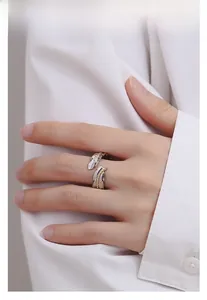 Detailed view of silver and gold feather ring on hand with elegant white shirt