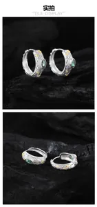 Close-up of S925 silver vintage earrings with green gemstone and gold floral engraving