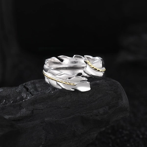 Two-tone gold and silver feather open ring with detailed texture on dark stone base