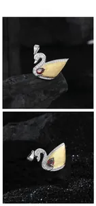 Detailed swan pendant featuring brushed metal texture and a pear-cut red gemstone inlay
