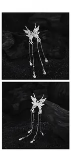 Détail du pendentif papillon argenté avec chaînes à pompons et breloques gouttes