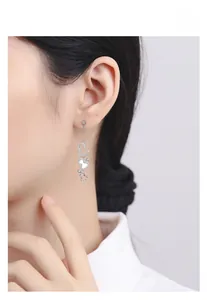 Detail of S925 silver long drop heart earrings with white shells and pavé diamonds