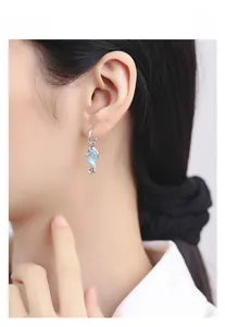 Detailed view of silver seahorse earrings with blue enamel worn by a model