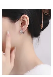 Détail des boucles d'oreilles plume en argent S925 avec texture gaufrée sur l'oreille