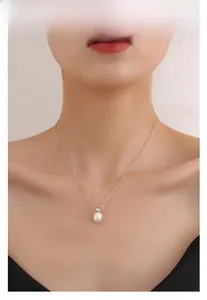 Gros plan d'un collier en argent S925 avec une perle d'eau douce blanche sur un mannequin
