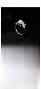 Detail of silver feather ring with micro-pave crystals and white pearl on black stone