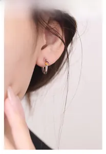 Dettaglio dell'orecchino a cerchio in argento S925 con zircone arancione sul lobo della modella