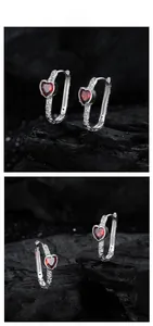 Detailed macro view of S925 silver heart earring with red zircon and embossed patterns