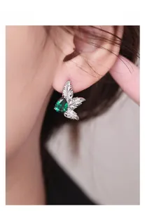 Macro detail of S925 silver leaf stud earring with pear-cut green zircon on ear