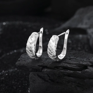 Vue macro des boucles d'oreilles en argent S925 avec texture tissée et petits zircons
