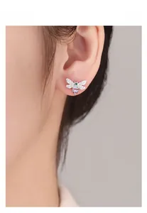 Macro detail of a silver bee stud earring with colorful gemstones on a female model