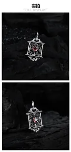 Détail d'un pendentif en argent S925 avec sculptures creuses et pierre de zircon rouge