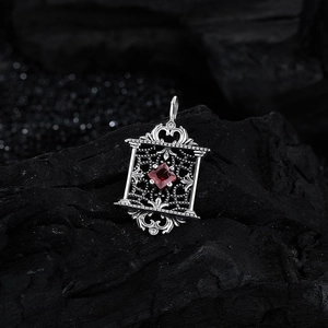 Pendentif vintage en argent S925 avec zircon rouge sur fond minéral texturé sombre