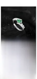 Macro shot of oval green zircon ring with crown-like pavé diamonds on textured background