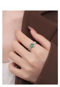 Close-up of S925 silver ring featuring an oval green gemstone and wavy diamond-set band