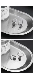 Macro detail of S925 sterling silver hoop earrings with detachable gear charms and blue stones