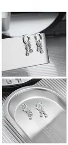 Close-up of S925 sterling silver drop tassel earrings with white zircon on a metal tray
