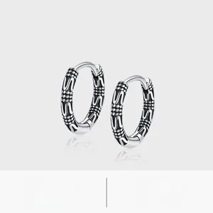 Macro shot of S925 silver hoop earrings with vintage vine patterns and punk chain details