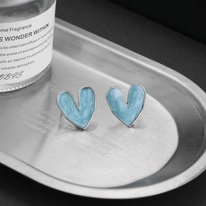 Close-up of S925 sterling silver heart studs with blue enamel sand texture on a metal tray