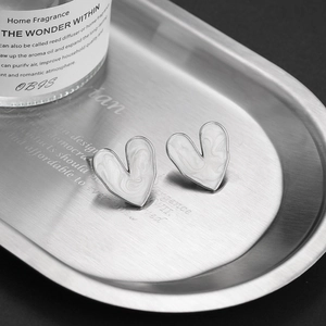 Minimalist S925 sterling silver heart studs with white enamel on a brushed metal tray