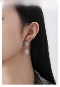 Dettaglio di orecchini in argento S925 con pizzo e gemme indossati da una modella