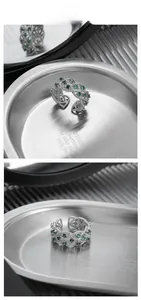 Detailed view of S925 silver hollow ring with green zircon stones on a metal tray