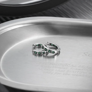 S925 sterling silver hoop earrings with heart-shaped green zircon on a metal tray