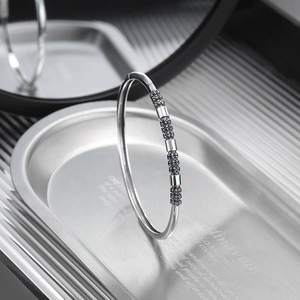 Detailed close-up of a silver bangle featuring colorful micro-pave cubic zirconia accents