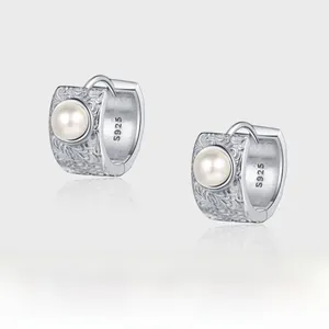 Macro shot of S925 sterling silver pearl earrings with embossed vintage floral patterns