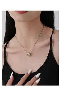 Detailed close-up of a two-tone silver and gold clover pendant necklace on a model